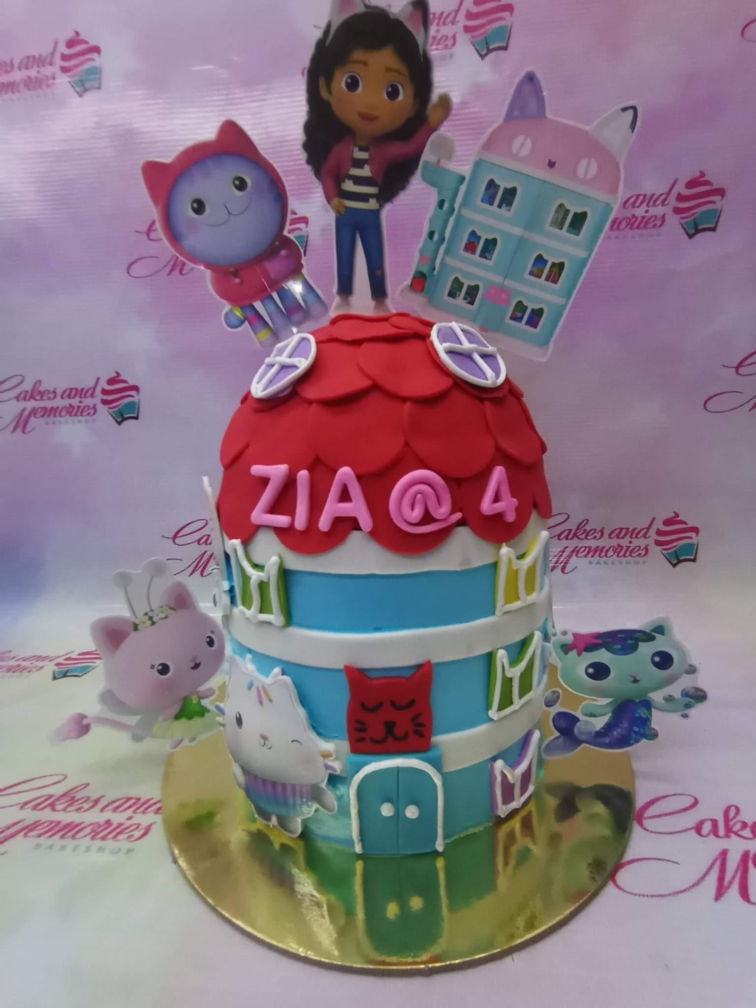 Gabby's Dollhouse themed blue and white fondant cake with a red scalloped roof and character printouts.