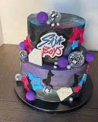 Two-tier galaxy themed cake with purple, blue, and black icing, disco balls, and music note decorations.