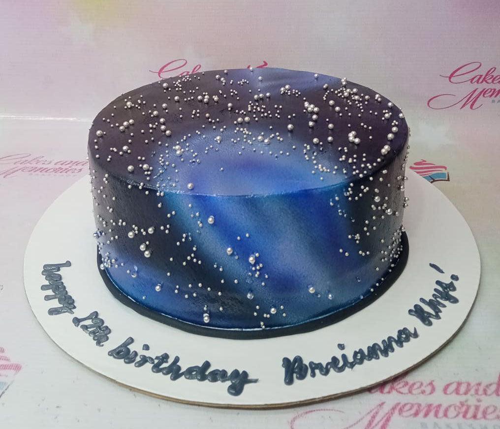 Galaxy themed birthday cake with blue and purple gradient icing and silver pearl sprinkles