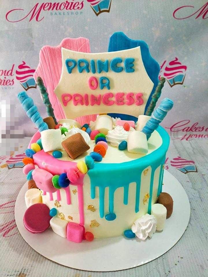 Gender reveal cake with pink and blue icing drips, marshmallows, and a Prince or Princess sign.