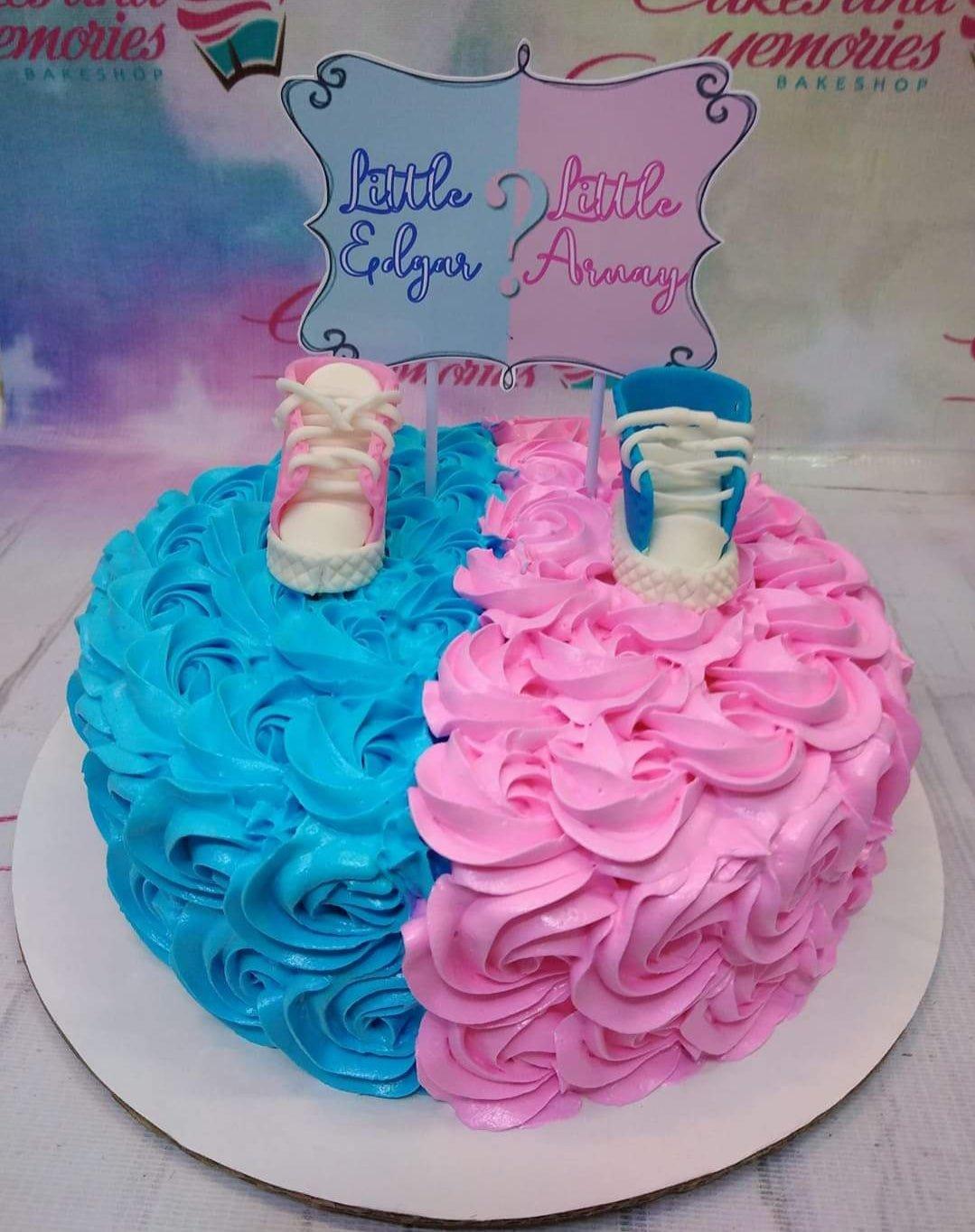 Gender reveal cake with blue and pink icing rosettes, featuring a 'Little Edgar or Little Amay' sign and baby shoes toppers.