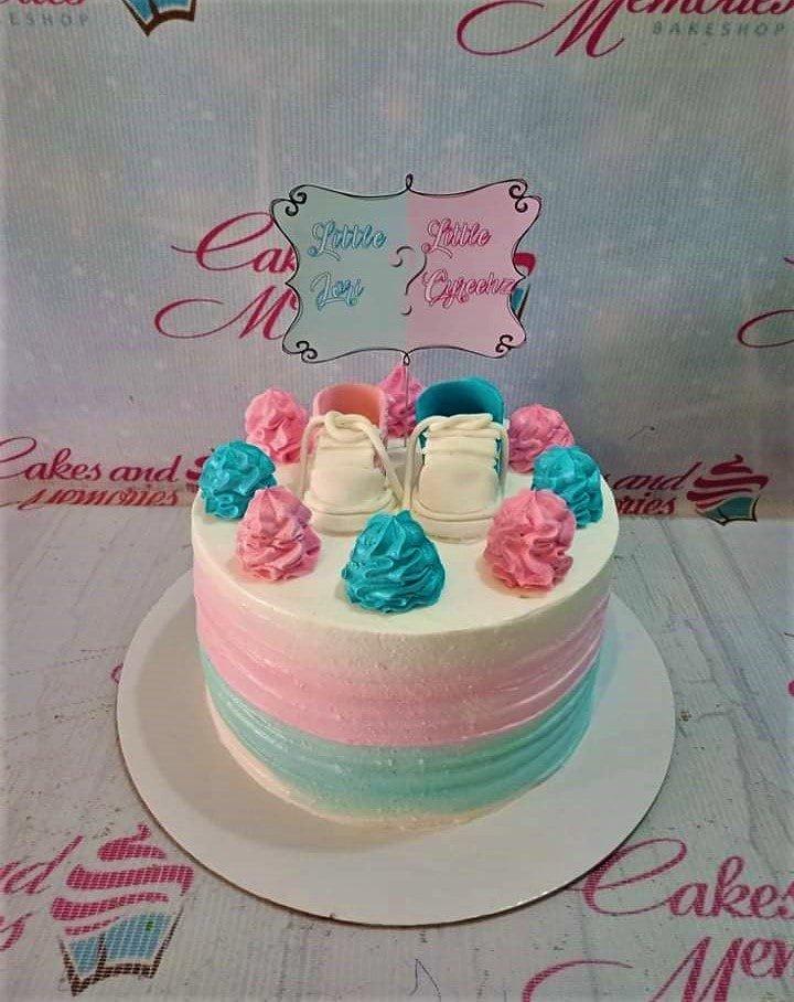 Gender reveal cake with pink and blue icing swirls, baby shoes toppers, and a Little Prince or Little Princess sign.