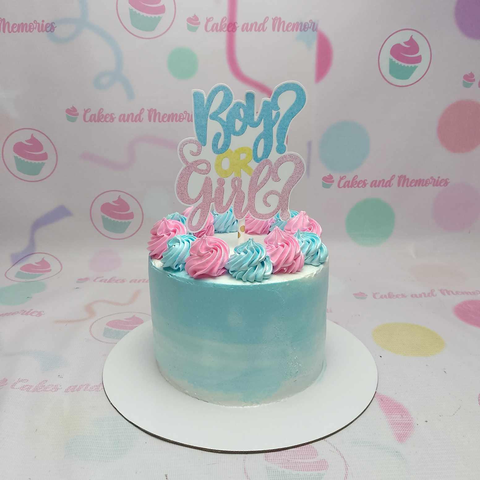 Blue and white gradient gender reveal cake with pink and blue icing rosettes and a Boy or Girl glitter topper.