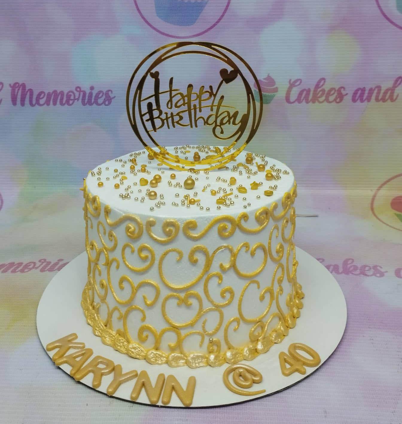 White 1-tier birthday cake with gold icing swirls, gold and silver sprinkles, and a gold Happy Birthday topper.
