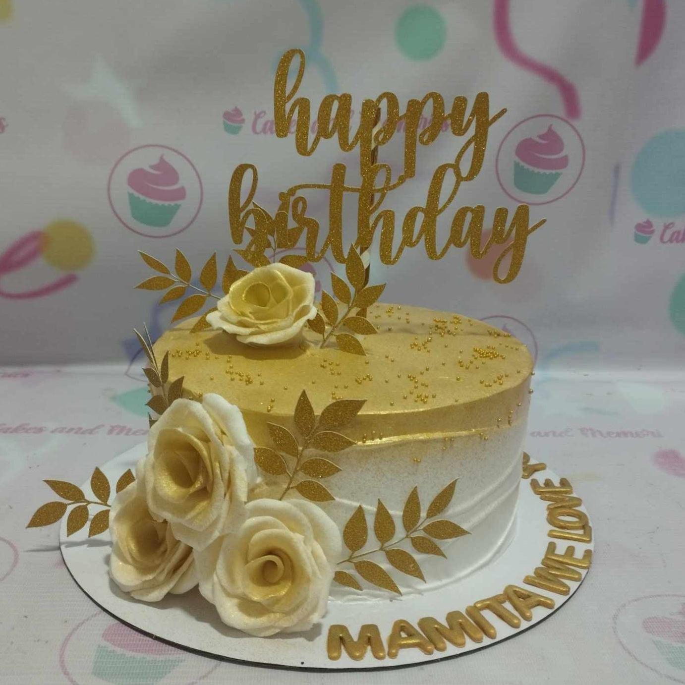 Elegant white and gold birthday cake with edible gumpaste roses, gold leaves, and a glittery Happy Birthday topper.