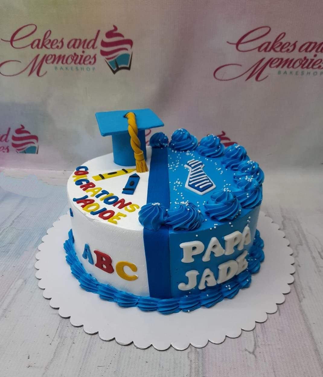 Blue and white split-design graduation and Father's Day cake with a graduation cap, tie, and colorful gumpaste letters.