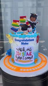 Blue and white gradient graduation cake for Blake with school-themed printouts including books, a student, and a graduation cap.