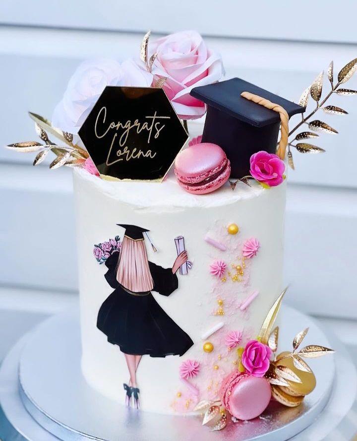 White tall cake with a graduation theme featuring a printout of a graduate, a 3D fondant graduation cap, pink macarons, and gold leaf accents.
