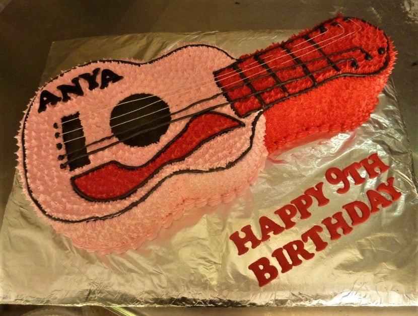 Guitar shaped birthday cake with pink and red icing rosettes and black string details for Anya's 9th birthday.