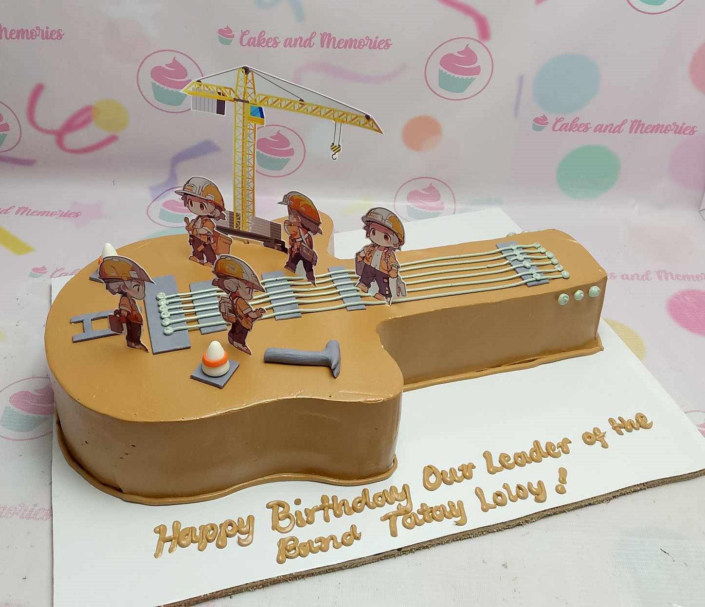 Guitar shaped cake with construction worker printouts and a crane topper for a birthday celebration.
