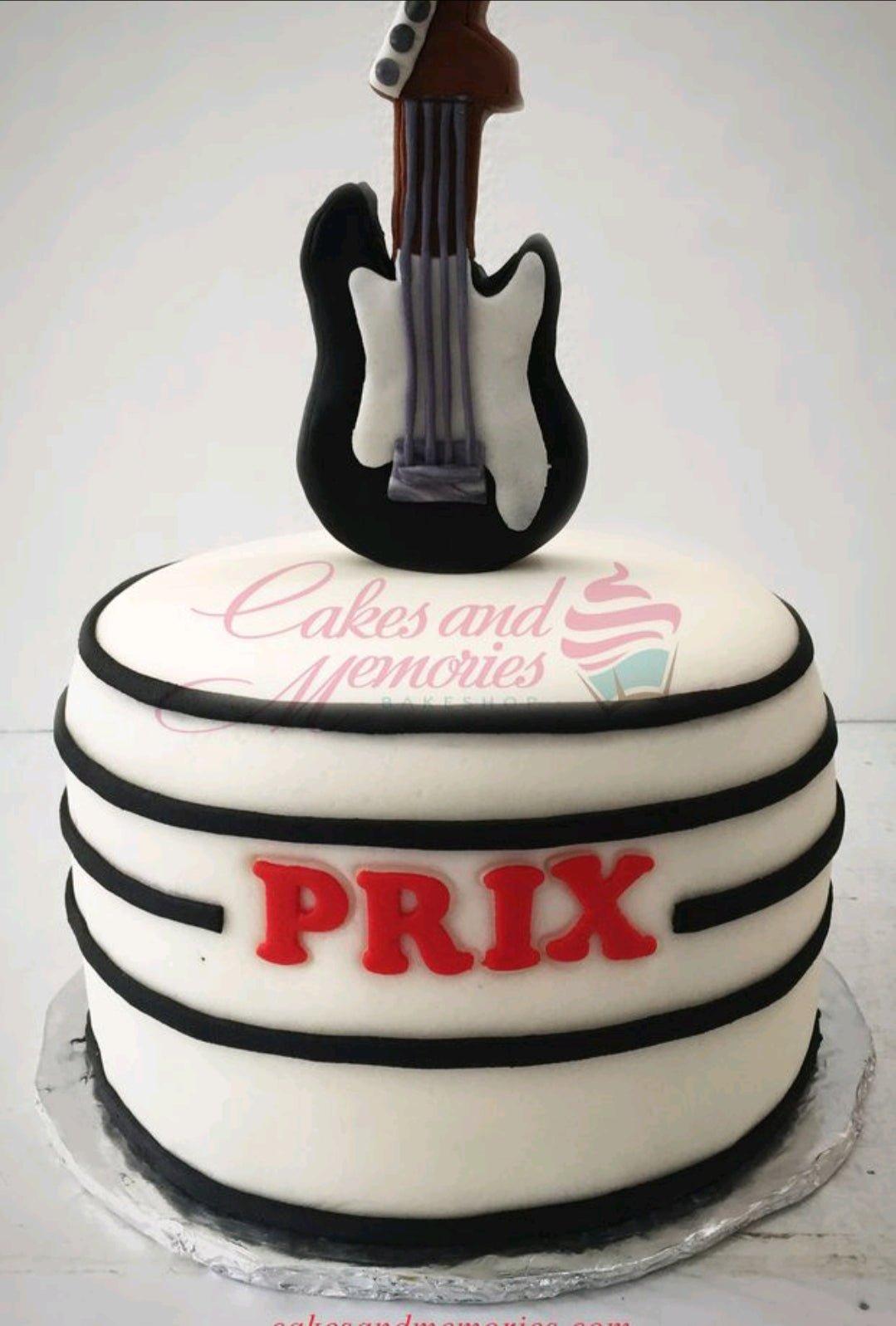 White fondant cake with black horizontal stripes and a 3D fondant electric guitar topper with the name PRIX in red.
