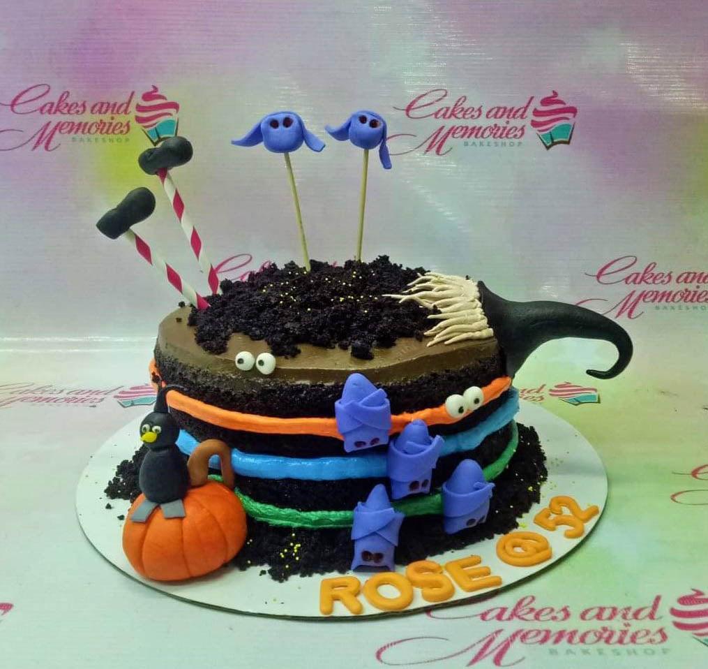 Halloween themed chocolate cake with orange pumpkin, black cat, purple ghosts, and colorful icing stripes.