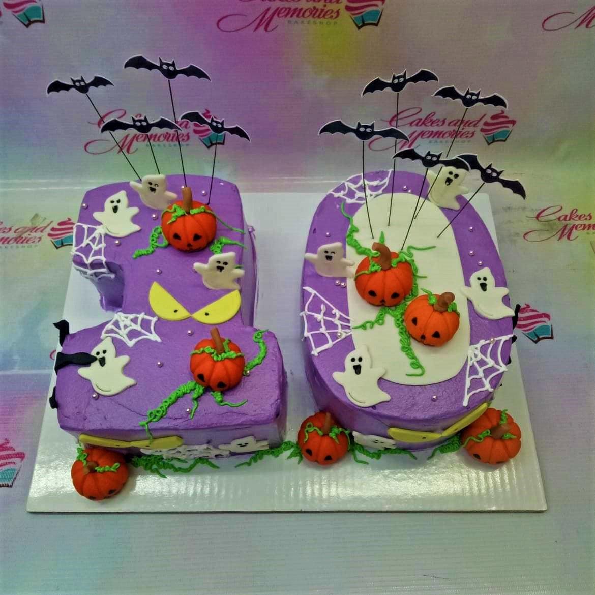 Purple Halloween number cake shaped like 10 with fondant pumpkins, ghosts, and bat printouts.