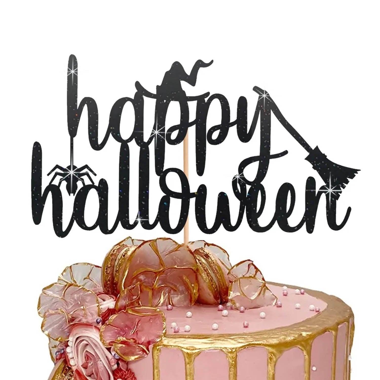 Pink Halloween cake with gold drip, macarons, and a black glittery Happy Birthday topper featuring a witch and spider.