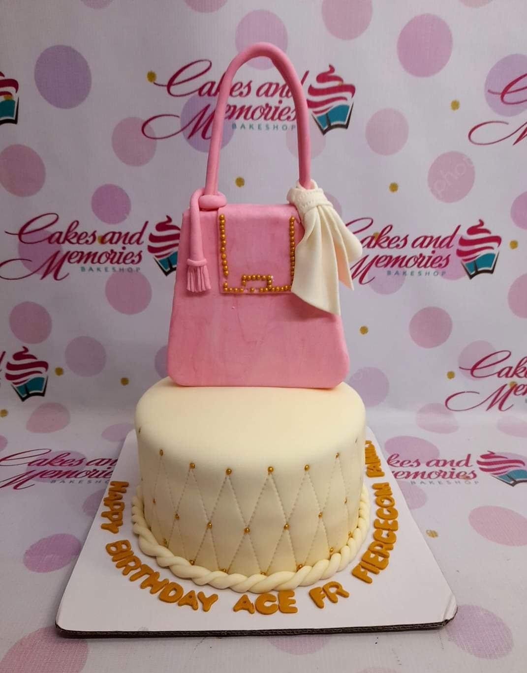 Two-tier pink and ivory designer handbag cake with gold quilted details and a large pink fondant purse topper.