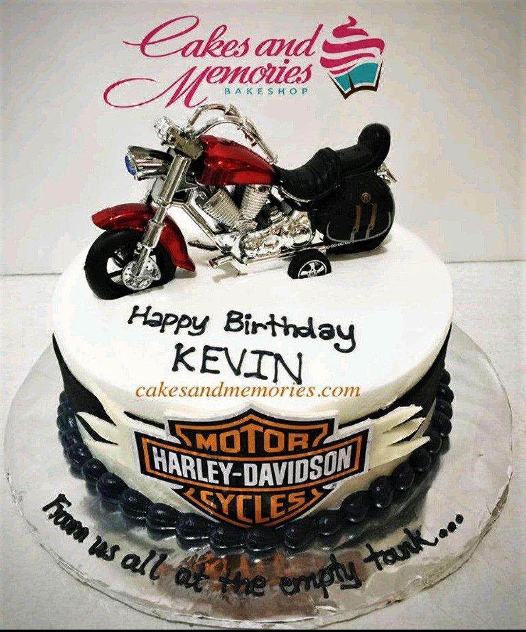 Harley-Davidson themed birthday cake with a red and silver motorcycle toy topper and black icing borders.