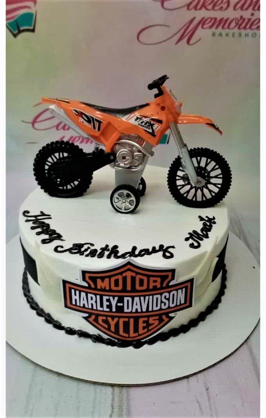 White 1-tier Harley-Davidson themed birthday cake with an orange toy dirt bike topper and black icing borders.
