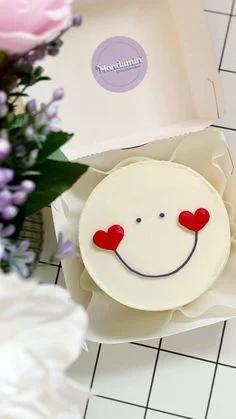 White bento cake with a minimalist red heart smiley face design in a white box.