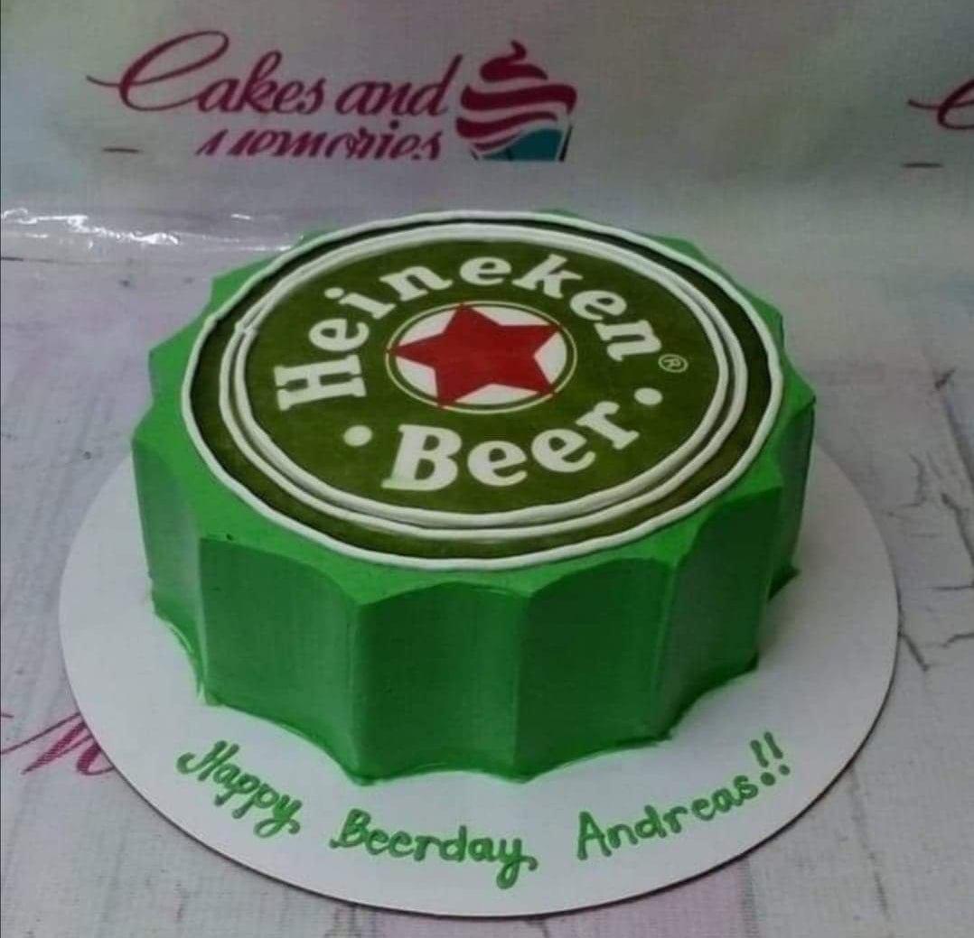Green Heineken beer bottle cap themed cake with a large printed logo on top and a personalized message on the base board.