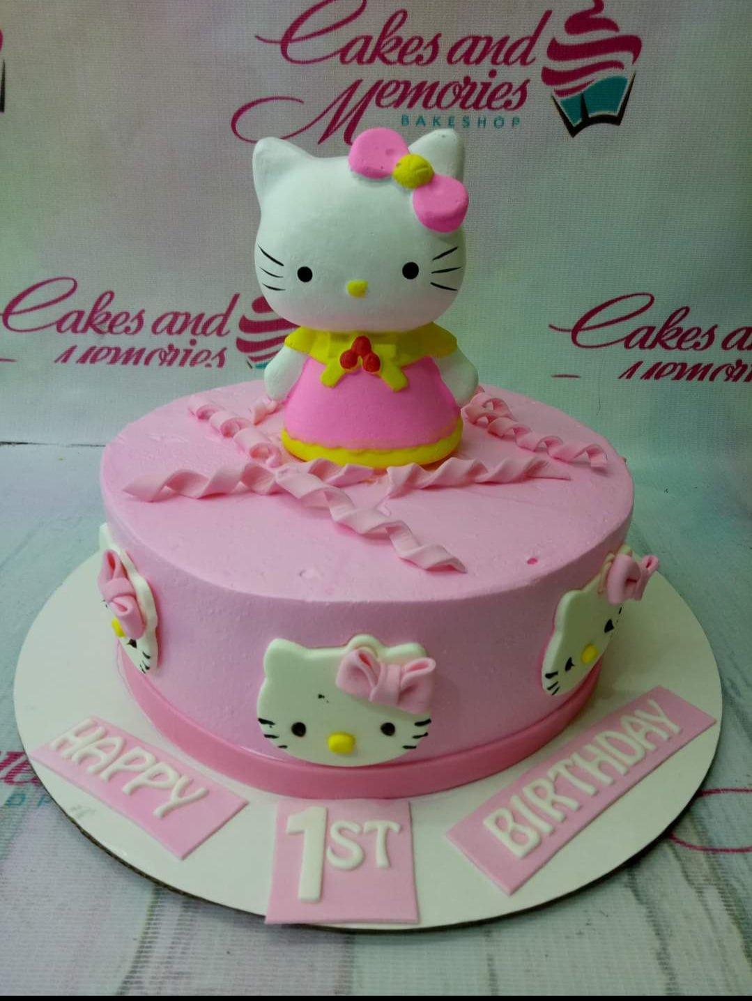 Pink Hello Kitty birthday cake with a large 3D fondant Hello Kitty topper and smaller Hello Kitty faces on the side.