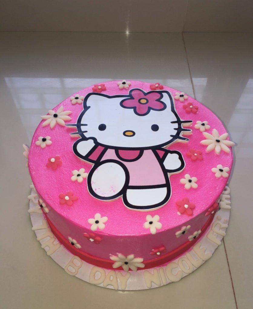 Pink Hello Kitty birthday cake with white and pink fondant flowers and a large Hello Kitty printout topper.