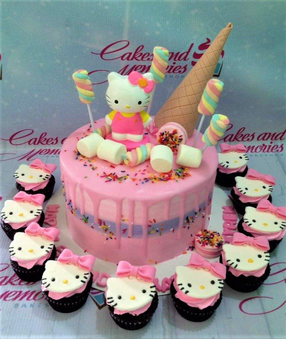 Pink Hello Kitty themed cake with ice cream cone topper, marshmallows, and matching cupcakes.