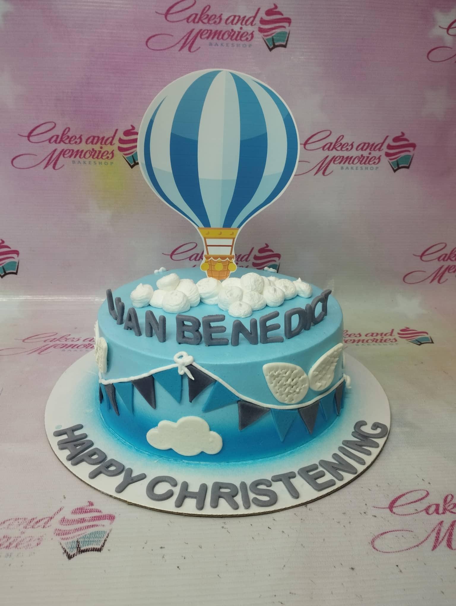 Blue and white hot air balloon christening cake with fondant clouds and bunting decorations.
