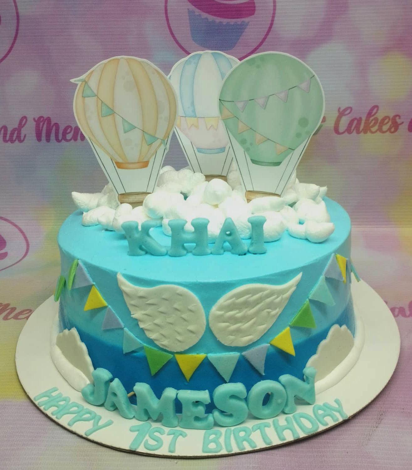 Blue gradient hot air balloon birthday cake with white fondant clouds and colorful bunting for Khai Jameson's 1st birthday.