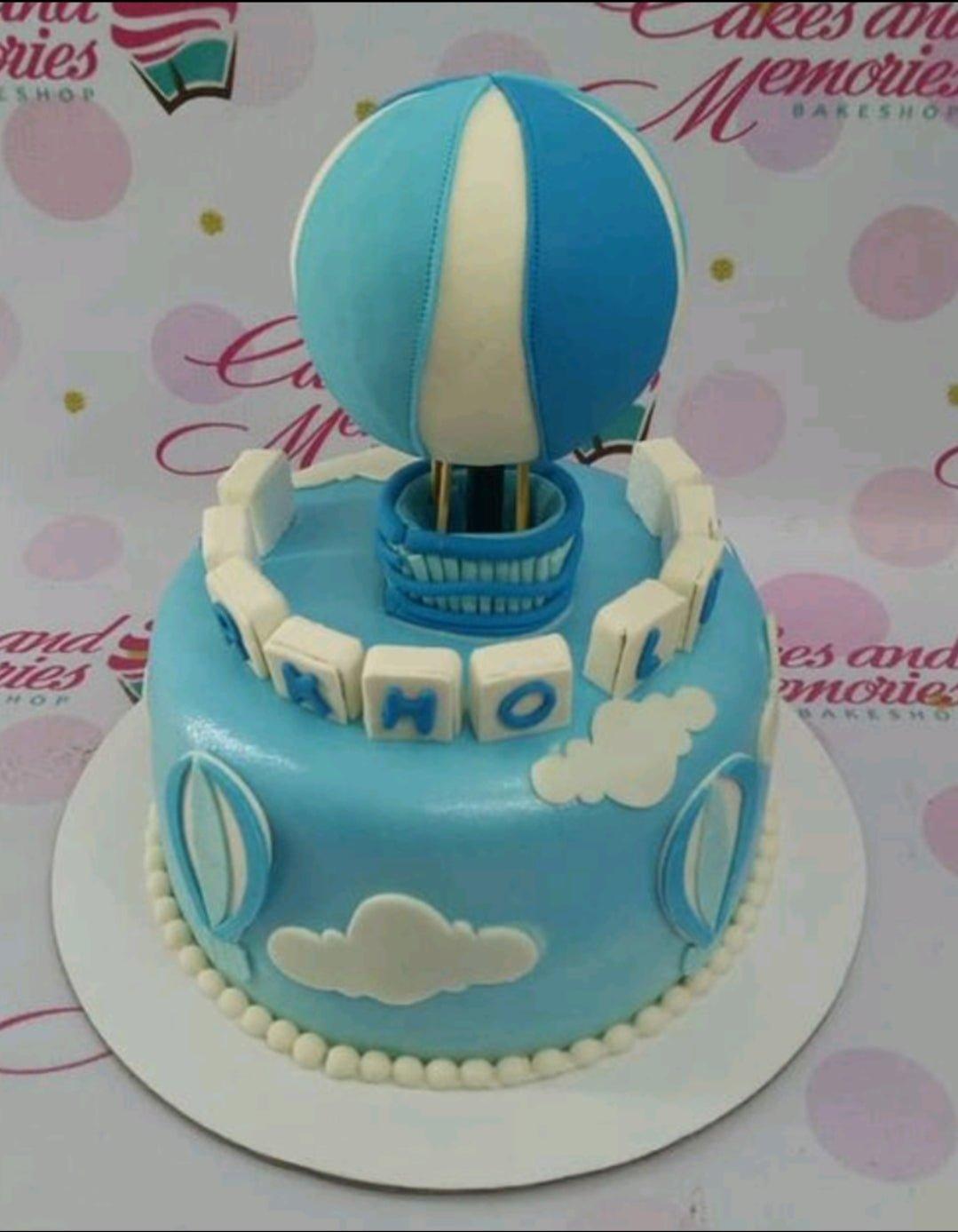 Light blue fondant hot air balloon cake with white clouds and blue balloon accents