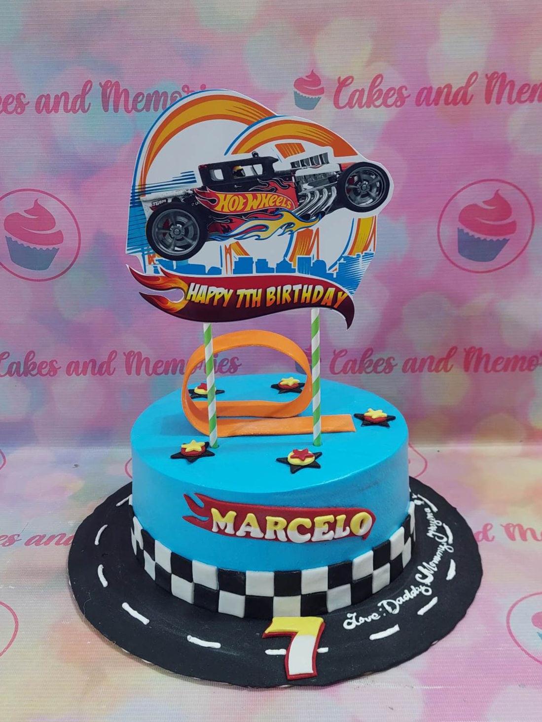 Blue Hot Wheels themed birthday cake with a checkered border and a large car printout topper.
