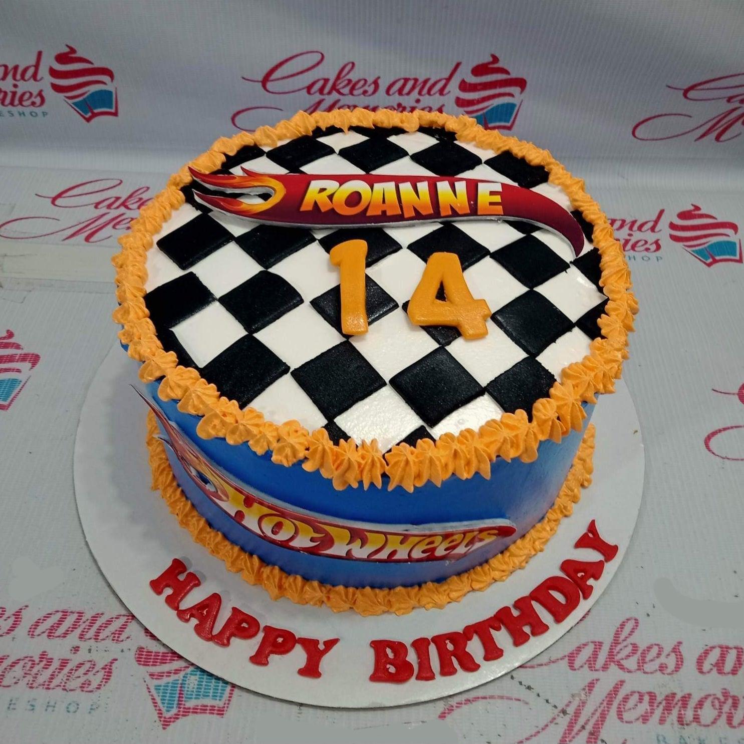 Hot Wheels themed birthday cake with a black and white checkered top, blue sides, and orange icing borders for Roanne's 14th birthday.