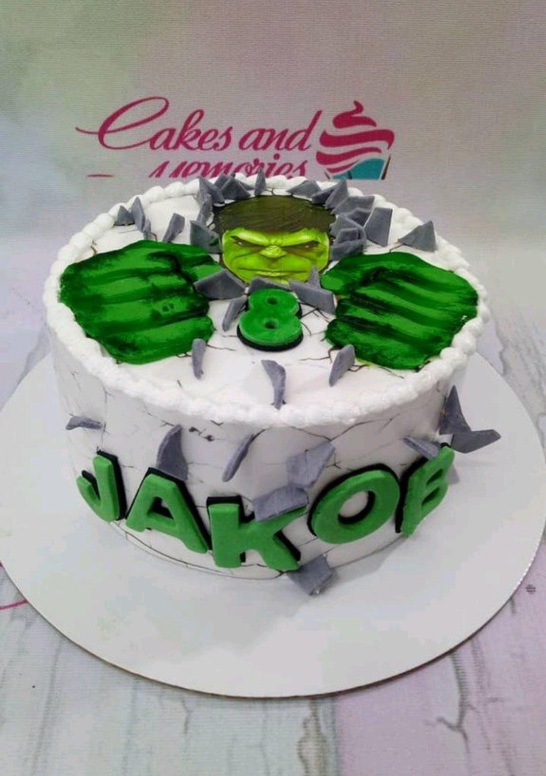 Hulk themed birthday cake with green fist toppers and grey stone accents on white icing