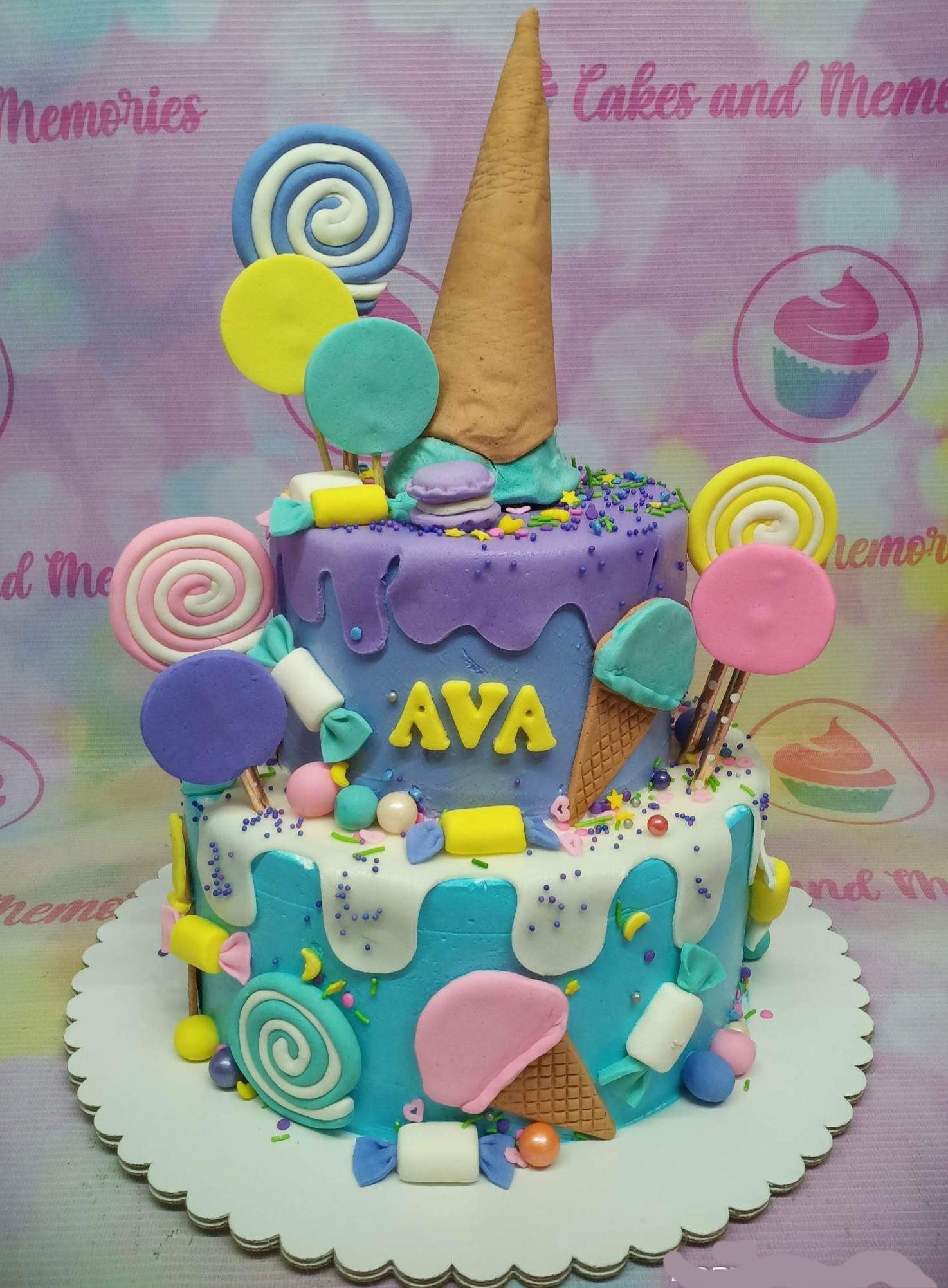 Colorful 2-tier ice cream and candy themed birthday cake with purple and blue icing drips and fondant lollipops.