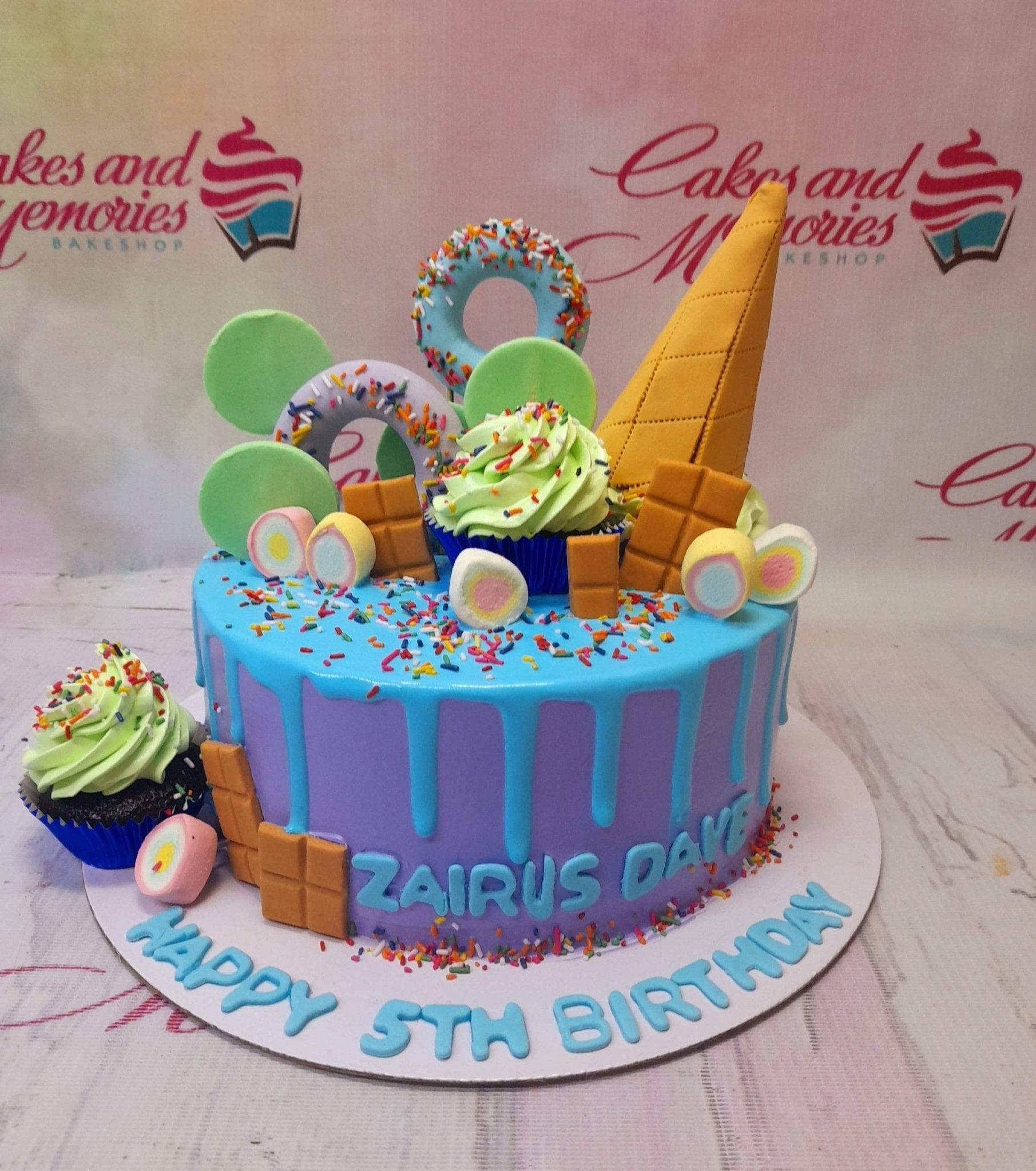 Purple and blue drip cake with ice cream cone, donuts, chocolate bars, and marshmallows for a 5th birthday.
