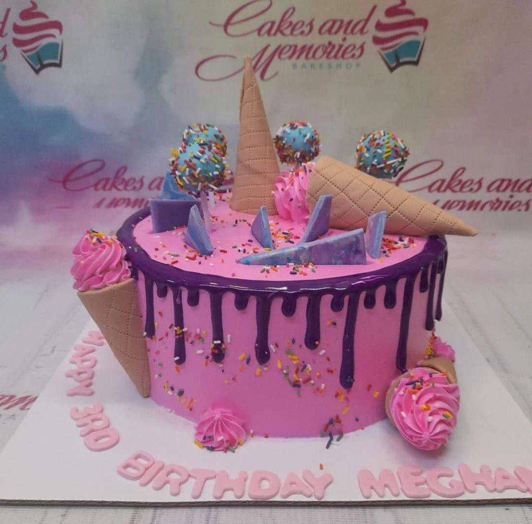 Pink ice cream themed birthday cake with purple drip, cake pops, and waffle cones for Meghan's 3rd birthday.