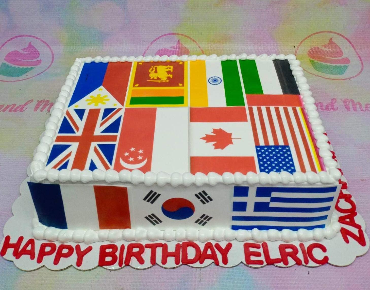 Square white cake decorated with various national flags on top and sides with red birthday message on the base board.