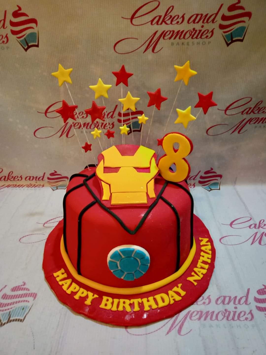 Iron Man themed red fondant cake with yellow stars and arc reactor detail for an 8th birthday celebration.