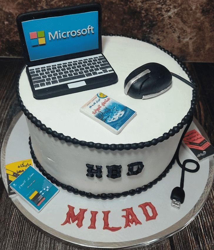 A white 1 tier cake featuring a fondant laptop and mouse, printed computer science books, and black beaded icing.