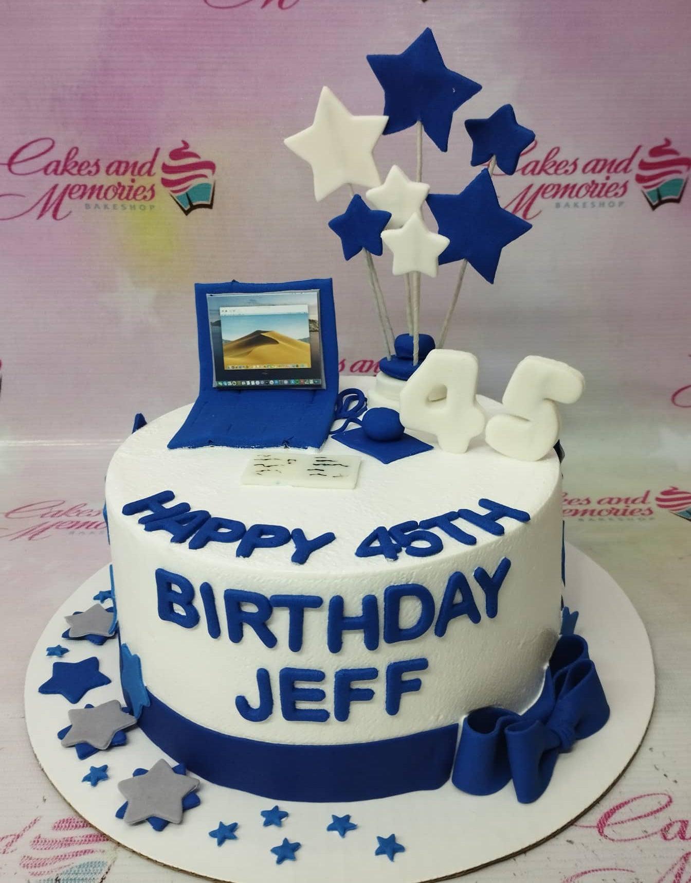 White 1-tier birthday cake for Jeff featuring a blue fondant laptop, white and blue stars on sticks, and a large white number 45 topper.