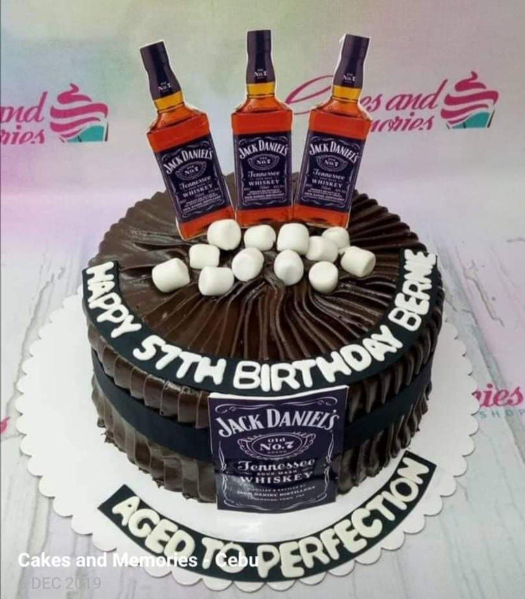 Chocolate birthday cake with Jack Daniels bottle printouts, marshmallows, and a black fondant band with white text.