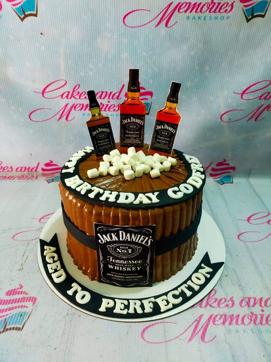Brown barrel-style Jack Daniels themed cake with whiskey bottle toppers and white marshmallows on top.