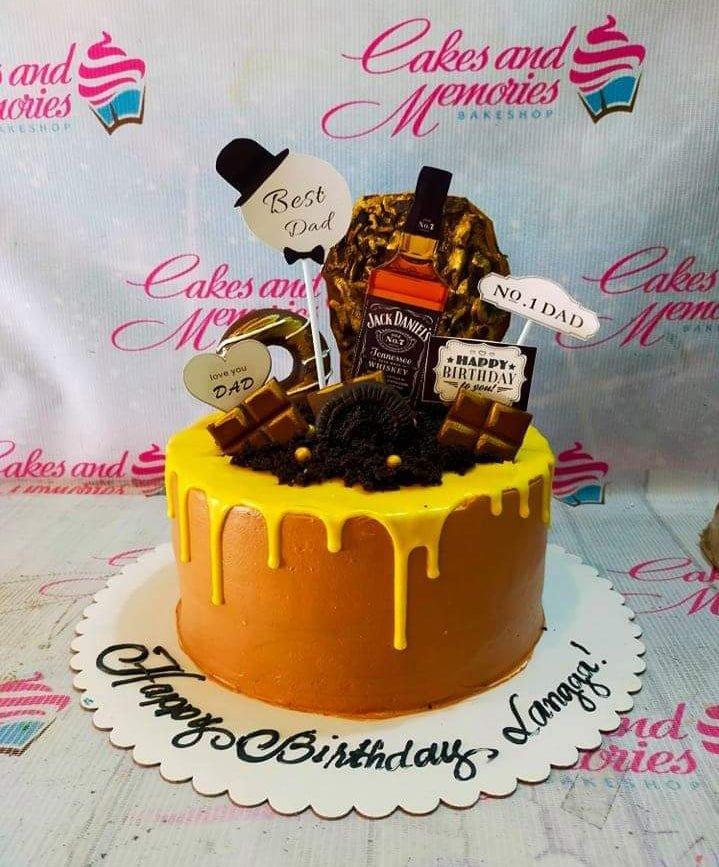 Brown and yellow drip cake for Dad with Jack Daniels bottle topper, chocolate bars, and Oreo cookies.