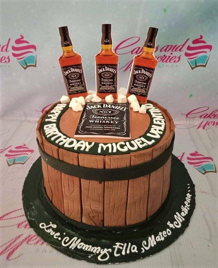 Jack Daniel's whiskey barrel cake with three miniature bottles on top and white fondant marshmallows.