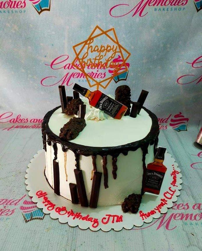 White 1-tier cake with chocolate drip, KitKat bars, and Jack Daniel's printout toppers for a birthday celebration.