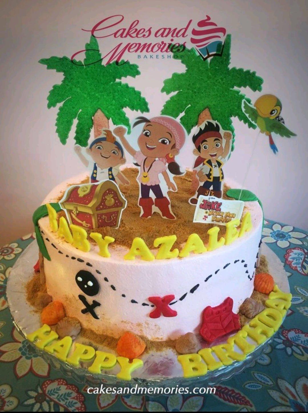 Jake and the Never Land Pirates themed birthday cake with character printouts, palm trees, and a treasure chest on a sandy icing base.