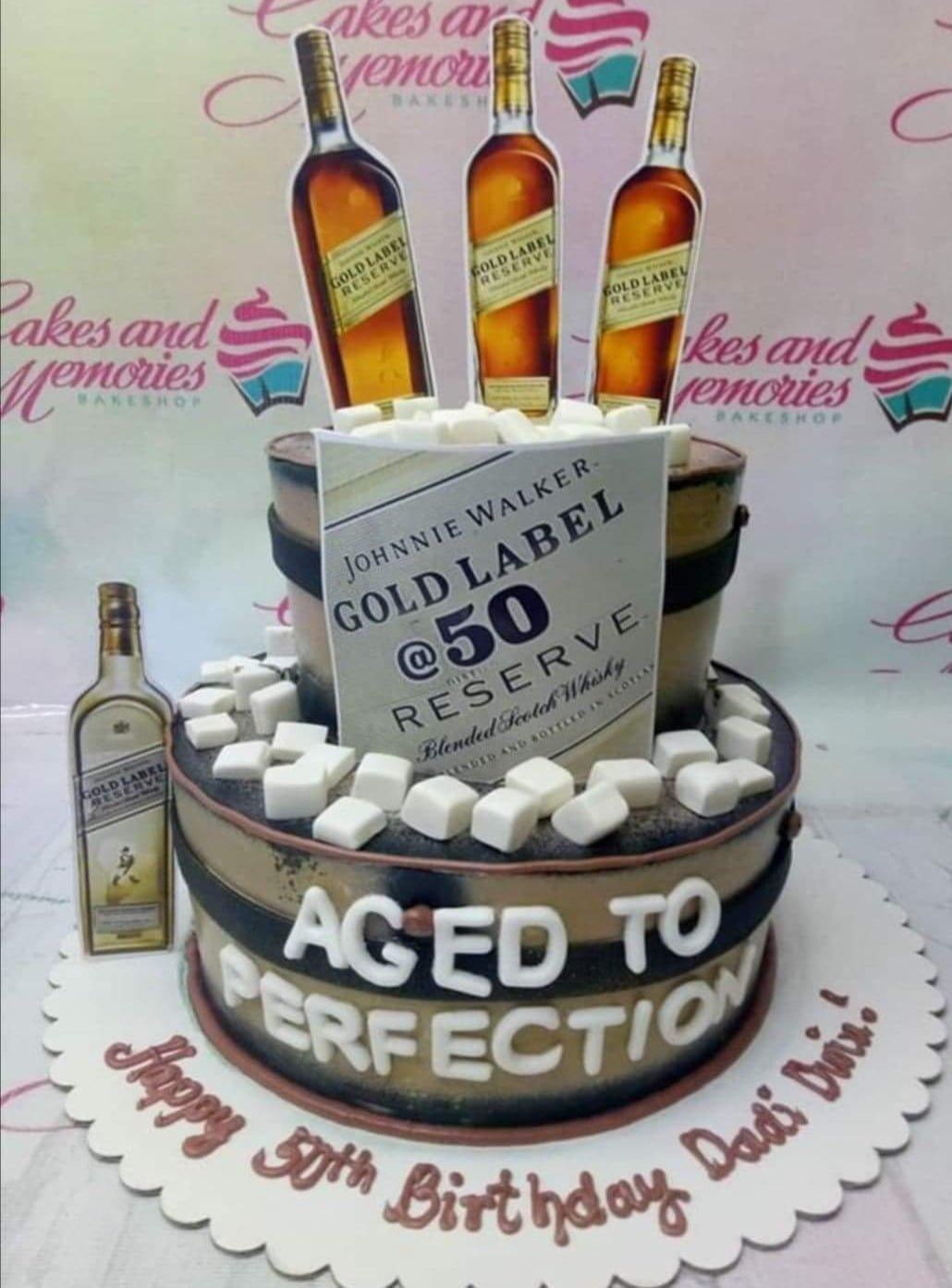 Two-tier Johnnie Walker Gold Label themed birthday cake with whiskey bottle printouts and white fondant ice cubes.