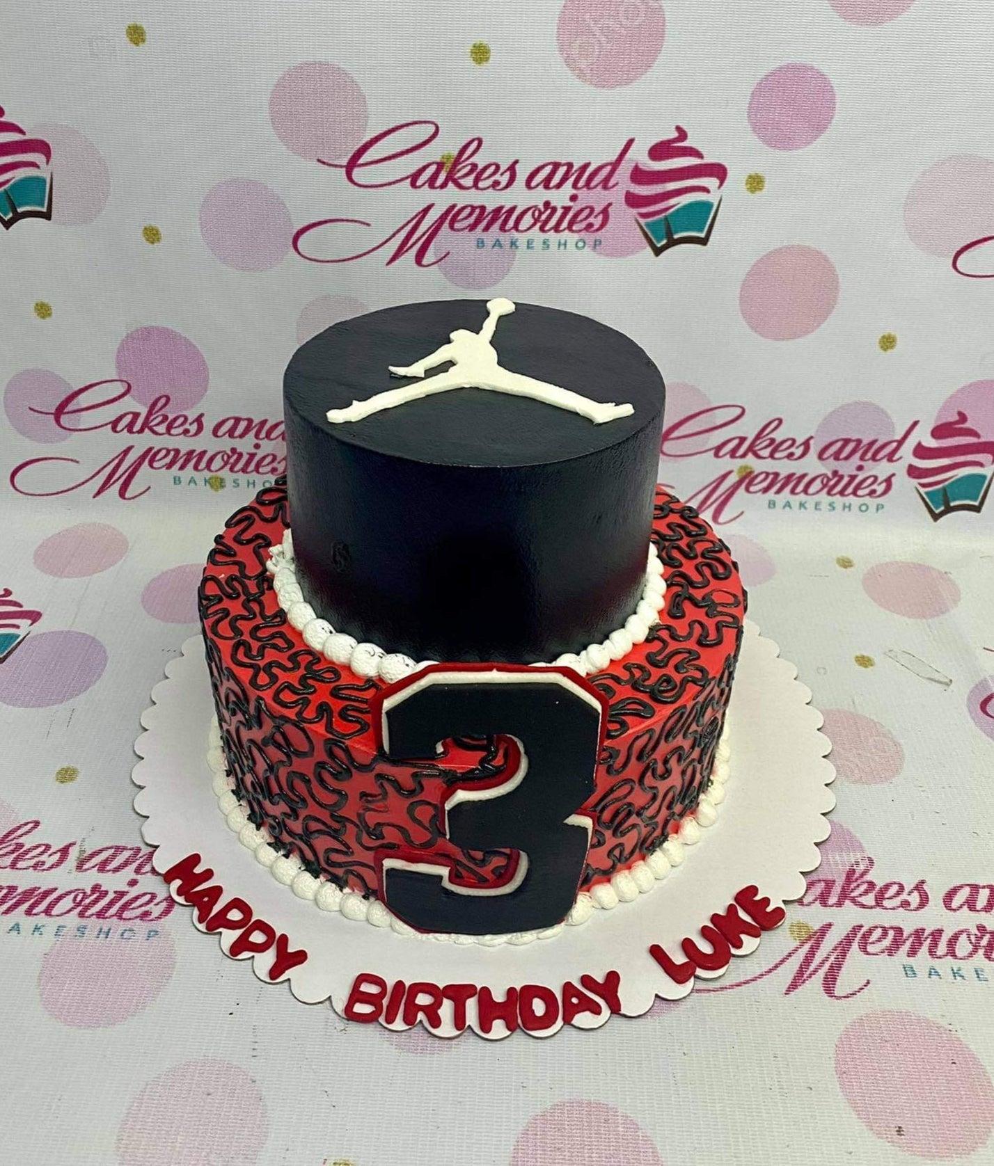 Two-tier Jordan themed birthday cake in black and red with a white Jumpman logo and a large number 3 on the side.
