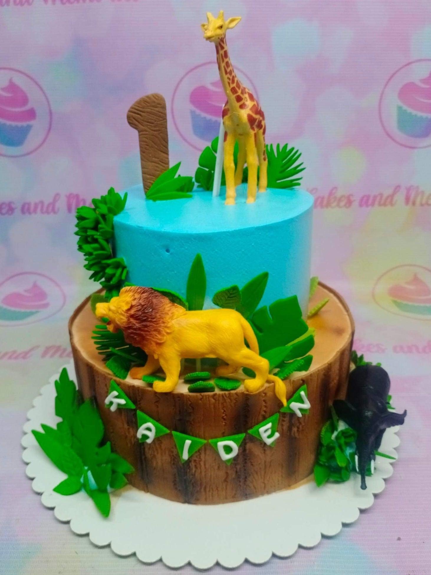 Two-tier jungle safari cake with a blue top tier and a wood-textured bottom tier featuring a lion, giraffe, and elephant.