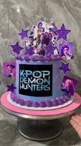 Purple and blue gradient K-Pop Demon Hunters themed cake with character printouts and glittery purple stars.