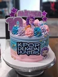 K-Pop Demon Hunters themed cake with pink and blue gradient icing, purple character printouts, and glittery number 10 topper.
